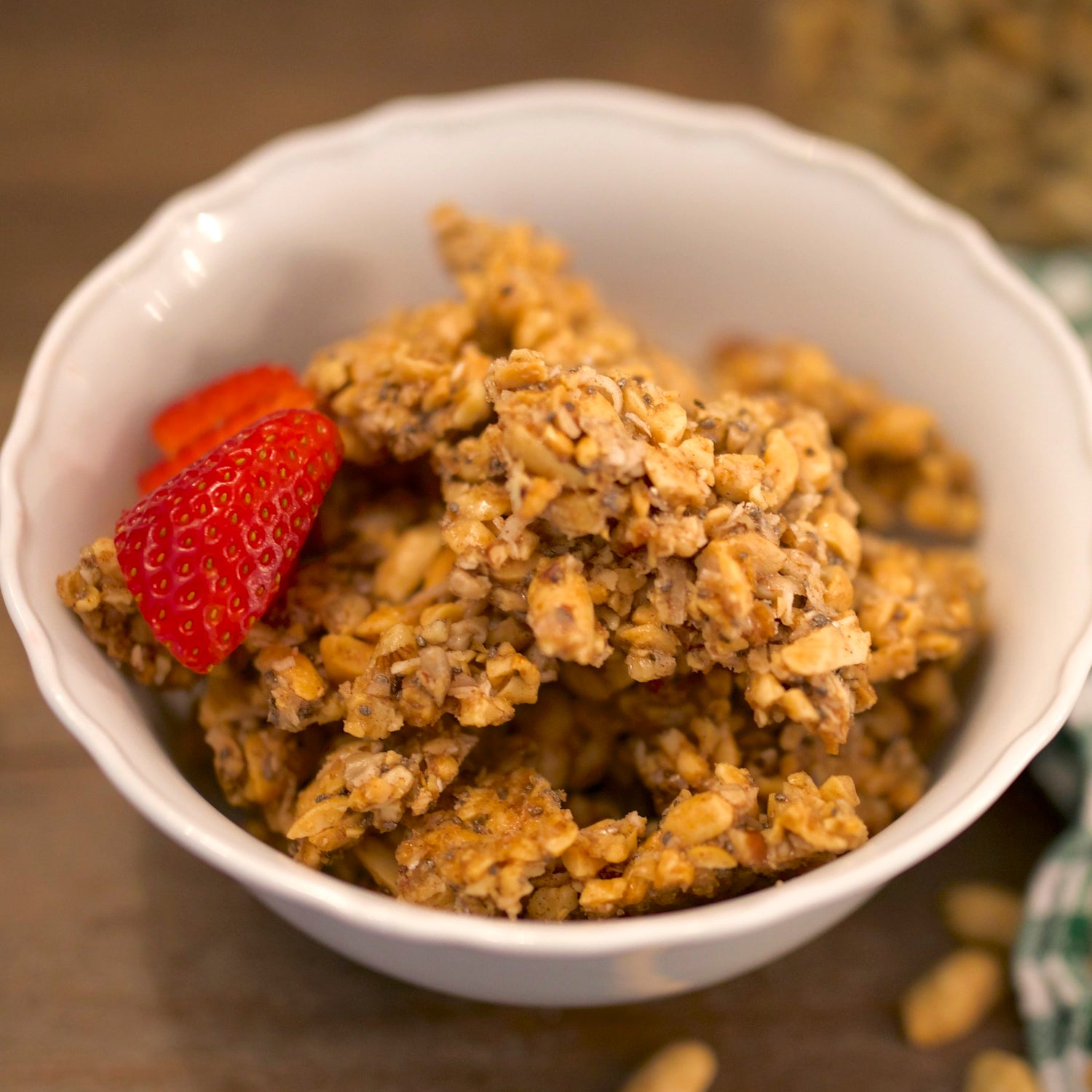 Grain-free peanut brittle granola in white bowl with strawberries